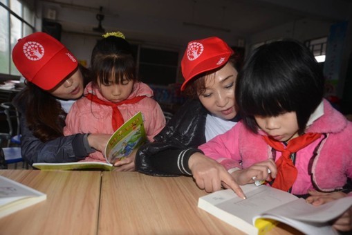 图为三生志愿者与孩子们共同阅读